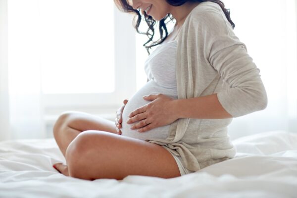 A pregnant woman sitting on a bed and holding her belly